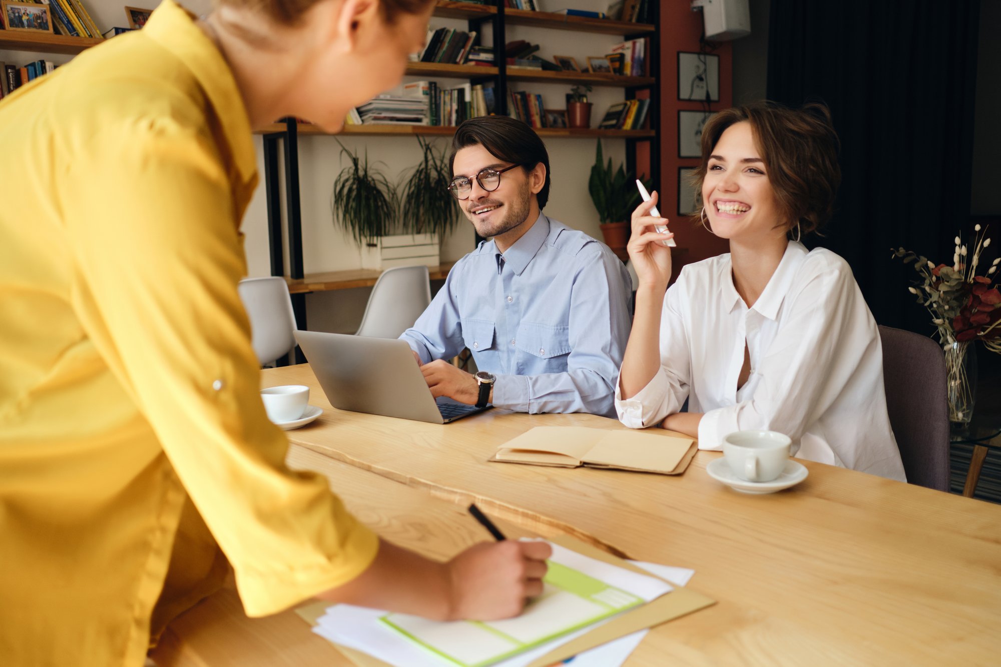 group-cheerful-business-colleagues-sitting-desk-with-laptop-papers-while-happily-talking-work-modern-office group-cheerful-business-colleagues-sitting-desk-with-laptop-papers-while-happily-talking-work-modern-office